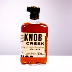 a bottle of knob creek whiskey sitting on a table with the label in front of it