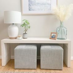 a white table with two stools next to it and a painting on the wall