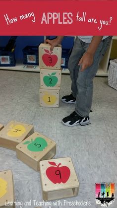 a young boy is playing with wooden blocks in the middle of an apple themed room