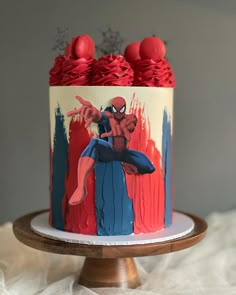 a spiderman cake with red icing and sprinkles on the top