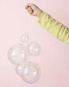 a person is holding three clear balls in the air with one hanging from it's string