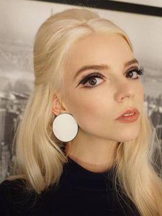 a woman with long blonde hair wearing large earrings