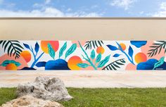 a large mural painted on the side of a building in front of a rock and grass area