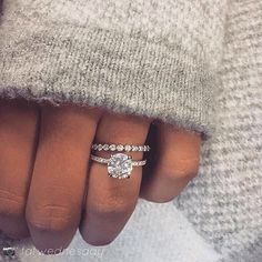 a woman's hand with a diamond ring on top of her finger and a sweater over her shoulder