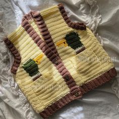 a knitted sweater with two birds on it sitting on top of a white sheet