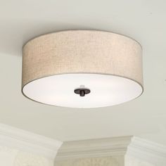 a white ceiling light with a beige shade on the top and an off - white wall behind it