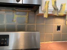 a kitchen with yellow tape on the wall next to an oven and stove top burner