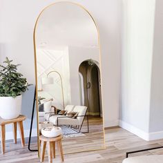 a large mirror sitting on top of a wooden floor next to a chair and table