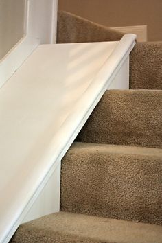 a cat sitting on the top of some stairs next to a hand rail and door