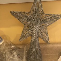 a silver star shaped christmas tree topper on a shelf next to other items and decorations