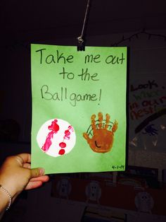 a hand holding up a green sign that says take me out to the ballgame