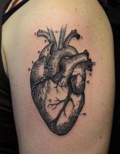 a black and white heart tattoo on the back of a woman's shoulder,