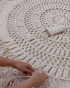 a woman is sitting on the ground with her hand on top of a crocheted doily