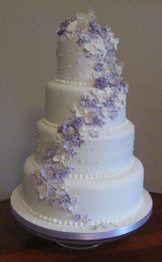 a three tiered white wedding cake with purple flowers