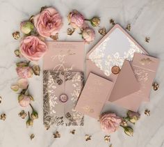 the wedding stationery is laid out with pink roses and gold foil on it's envelopes