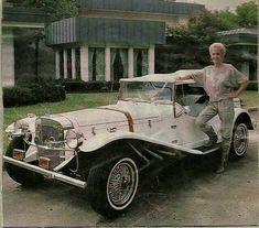 a man standing next to an old fashioned car