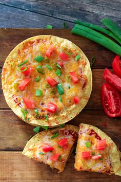 an omelet with tomatoes and green onions on a cutting board next to some cut up vegetables