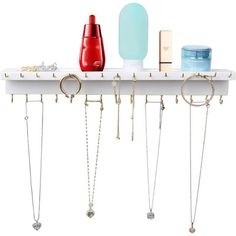 a white shelf with several necklaces and other items on the top, hanging from it's sides