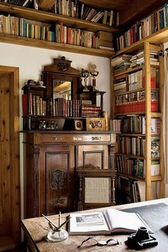 an old fashioned desk and bookshelf in a room with many books on the shelves