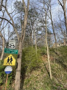 a couple of signs on the side of a hill next to some trees and grass