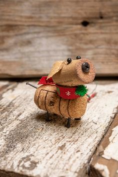 a small toy mouse with a red scarf around it's neck sitting on top of a piece of wood