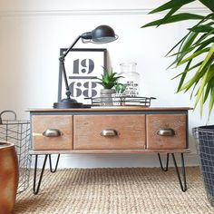 a wooden dresser with two drawers and a potted plant next to it on a rug