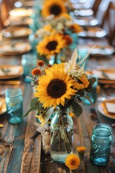 a long table with sunflowers and blue mason jars on it, along with place settings