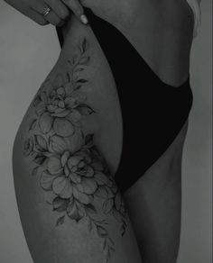 a woman's stomach with flowers on it and her hand holding the side of her thigh