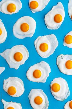 fried eggs are arranged in rows on a blue surface