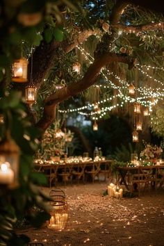 an outdoor dining area with candles and lights hanging from the trees, surrounded by greenery