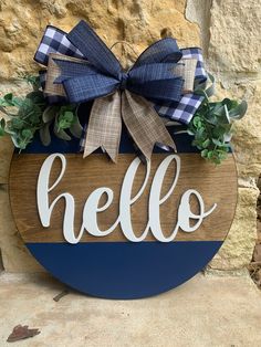 a wooden sign with the word hello painted on it and a bow hanging from it