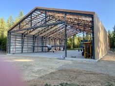 a large metal building sitting on top of a dirt field next to a parking lot