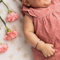 a baby laying on top of a bed next to pink flowers