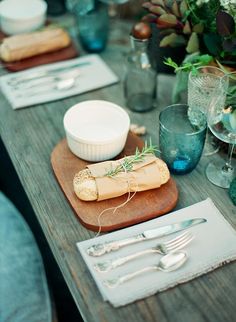 a wooden table topped with silverware and plates