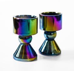 two shiny glass candlesticks sitting on top of each other in front of a white background