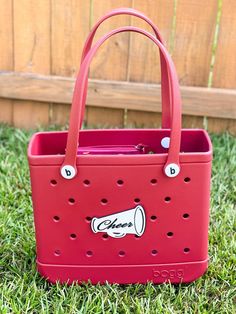 a red tote bag sitting in the grass