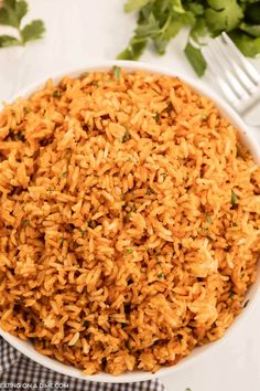 a white bowl filled with rice and garnished with parsley on the side