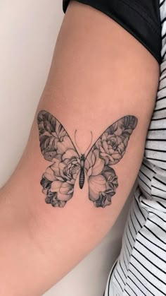 a woman's arm with a butterfly and roses tattoo on the back of it