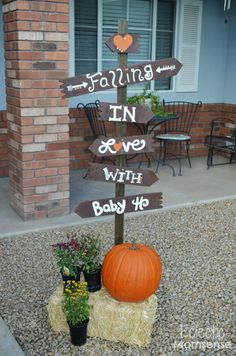 a wooden sign sitting on top of a pile of hay next to a pumpkin and potted plant