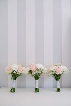 three vases filled with flowers sitting on top of a table next to a wall