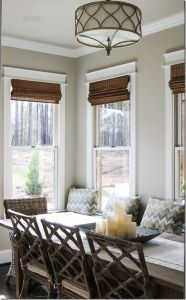 a dining room table with candles on it in front of two windows and some chairs