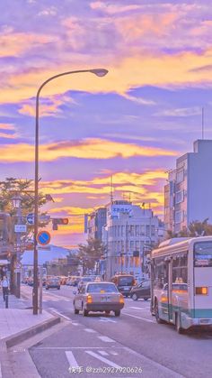 a city street with cars and buses on it at sunset or dawn, as the sun sets