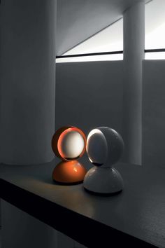 two white and orange lights sitting on top of a black table next to each other