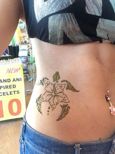 a woman with a flower tattoo on her stomach is standing in front of a store