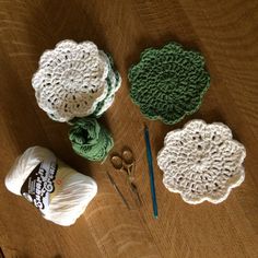 crocheted doily, yarn and knitting needles on a wooden table with scissors