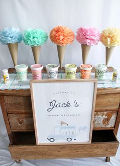 an ice cream stand with cones and flowers on it's display table for desserts