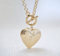 Heart Locket Toggle Necklace Details : - Heart locket for your photographs or secret messages - Thick round link chain, finished with a toggle clasp - Materials : 16K gold plated over brass - Necklace length : 18 inches - Heart Locket : 30 mm x 30 mm (~1.25 inches)- Locket inner dimension: 23 mm x 20 mm Gold Heart Pendant Toggle Necklace As Gift, Gold Toggle Necklace With Heart Charm As Gift, Gold Heart Charm Locket Necklace, Gold Round Locket Necklace With Heart Charm, Gold Medallion Toggle Necklace For Gift, Gold Medallion Toggle Necklace As Gift, Yellow Gold Medallion Toggle Necklace Gift, Gold Necklaces With Toggle Clasp For Wedding, Vintage Toggle Necklace With Toggle Clasp As Gift