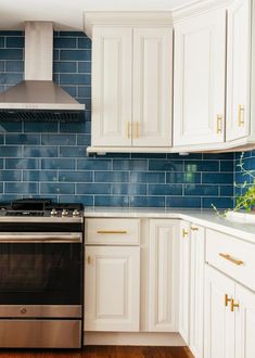 a stove top oven sitting inside of a kitchen next to white cabinets and wooden floors