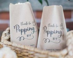 two paper bags with writing on them sitting in a basket next to a flower pot