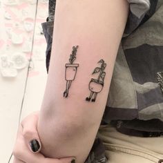 a person with a small tattoo on their arm holding a cup and potted plant